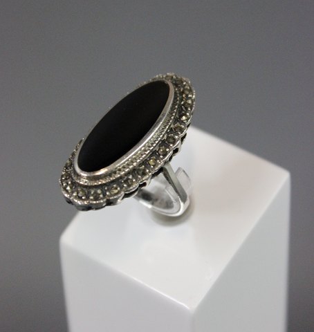 Sølv ring 925s med stor oval onyks, omkredset af similisten. Str 58.
5000m2 udstilling. 
